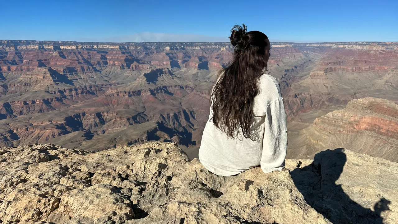 Lena sitzt auf einem Felsen am Rand des Grand Canyon